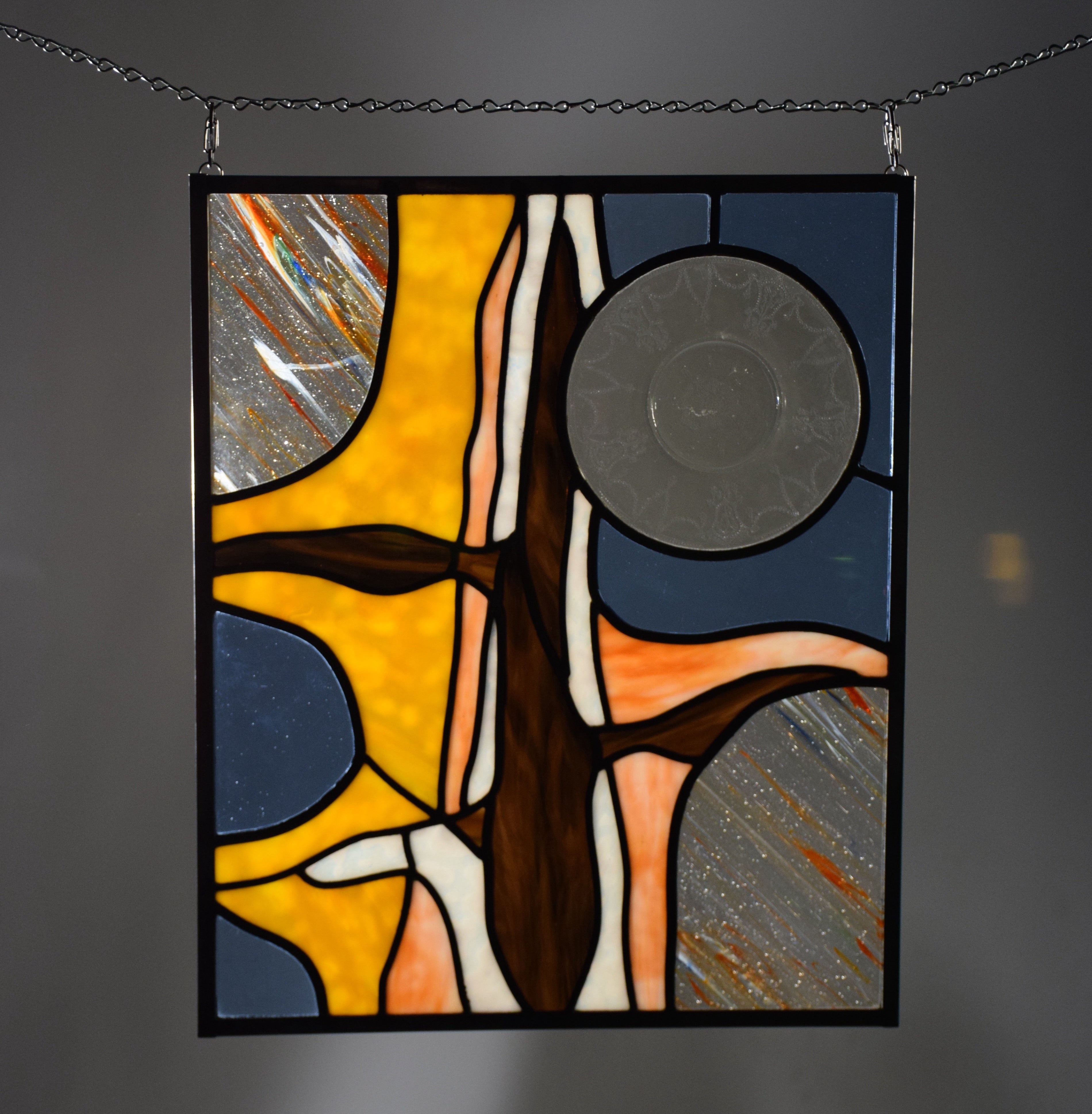 Abstract stained glass panel with geometric shapes on a dark background